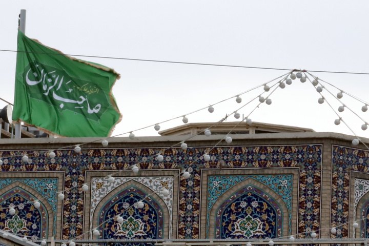 Imam Mahdi’s green flag next to Imam Reza shrine dome
